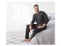 Un homme en pyjama noir assis sur un lit.
