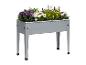 Un pot de fleurs en métal gris avec des pieds, rempli de fleurs.