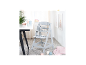 Chaise haute en bois gris clair avec plateau et harnais, à côté d'une table avec vaisselle pour enfants.