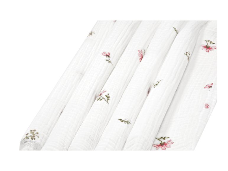 Tissu blanc plissé avec de petites fleurs roses et des motifs de feuilles brodés.