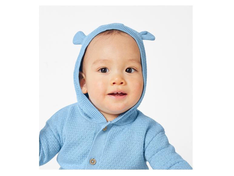 Un bébé portant un pull bleu tricoté à capuche.