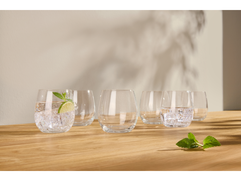 Verres avec eau, glace, citron vert et menthe sur une surface en bois.