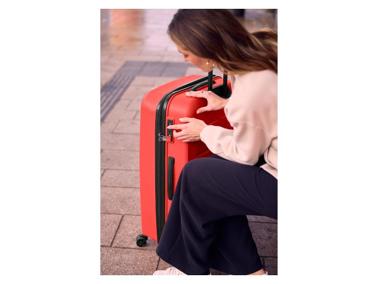 Femme réglant la serrure à combinaison sur une valise de voyage rouge.