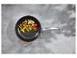 Poêle avec légumes rôtis sur fond gris.