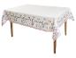 Nappe blanche avec motif floral et bordure festonnée rose sur une table en bois.