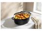 Cocotte ovale remplie de poulet rôti, de légumes et de tomates sur un comptoir.