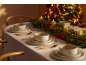 Table de Noël élégamment dressée avec de la vaisselle blanche, des couverts dorés et des décorations.