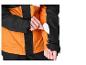 Une main insère une carte blanche dans une poche zippée sur la manche d'une veste orange et noire.
