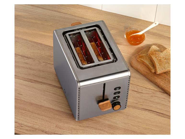 Grille-pain en acier inoxydable avec accents en bois, toasts et confiture sur un comptoir en bois.