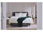 Chambre à coucher avec une parure de lit à motif d'arbres et un plaid vert foncé sur le lit.