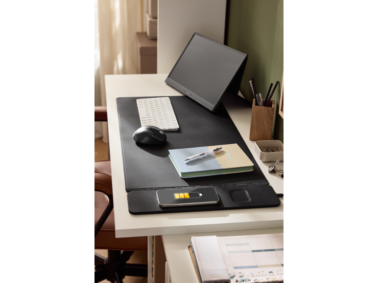 Un bureau moderne avec un écran portable, un clavier, une souris, un carnet et un téléphone en charge.