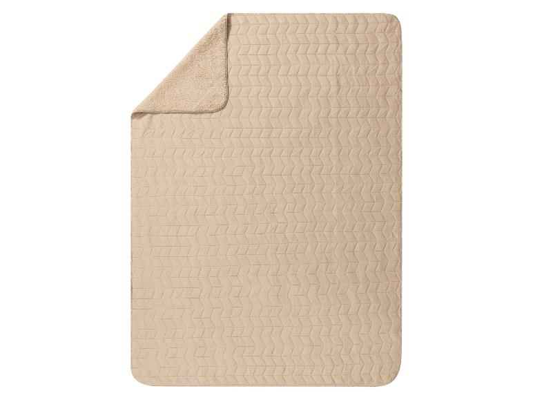 Couverture beige à motif géométrique et doublure en polaire douce.