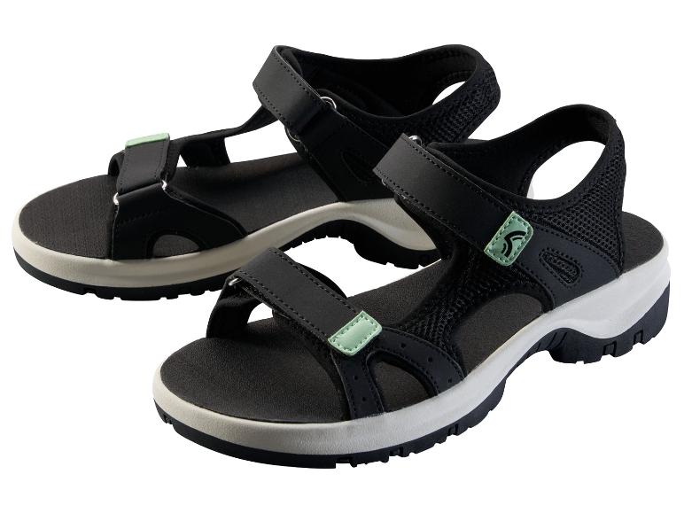 Une paire de sandales de sport noires avec des accents verts sur fond blanc.
