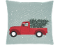 Coussin avec un camion rouge transportant un sapin de Noël et des cadeaux sous la neige.