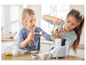 Deux filles cuisinent avec un robot de cuisine, du lait, du chocolat et de la farine.