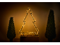Silhouette d'arbre de Noël illuminée avec deux arbres topiaires en pot.