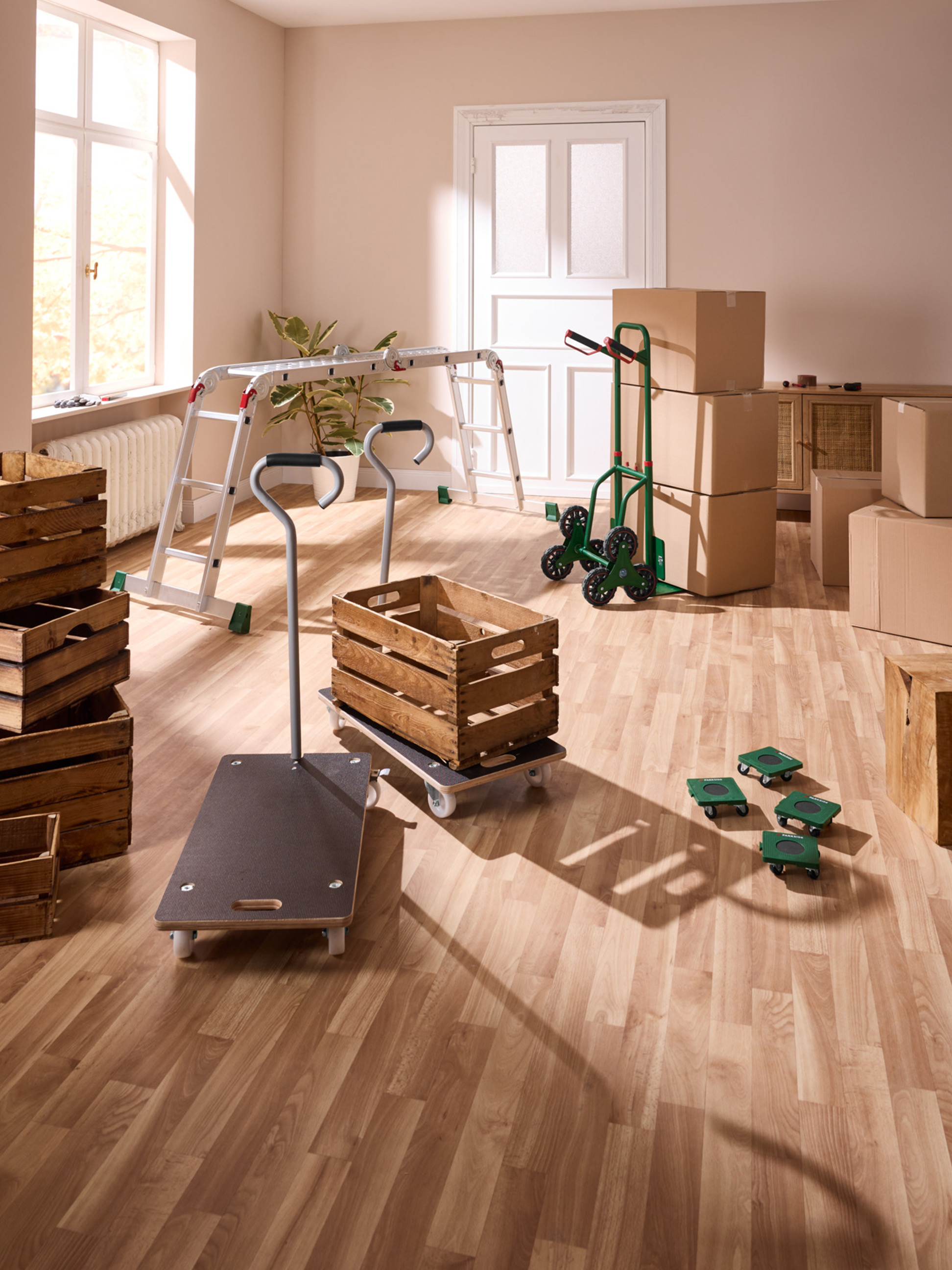 Chariots de transport et caisses en bois dans une pièce avec parquet, prêts pour un déménagement.