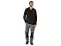Un homme portant un pull noir et un pantalon de travail gris.