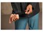 Un homme montre la manchette d'une veste noire avec une fermeture velcro.