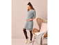 Une femme enceinte vêtue d'une robe grise et de collants noirs.