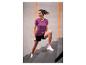 Femme en t-shirt de sport violet et short noir faisant de l'exercice dans les escaliers.