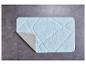 Un tapis de bain bleu clair avec un motif losange sur un sol en carrelage gris.