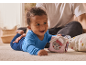 Bébé heureux en grenouillère bleue jouant avec un cube d'activités doux sur le tapis.