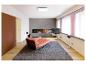 Salon moderne avec une chaise longue orange, une cheminée et une télévision