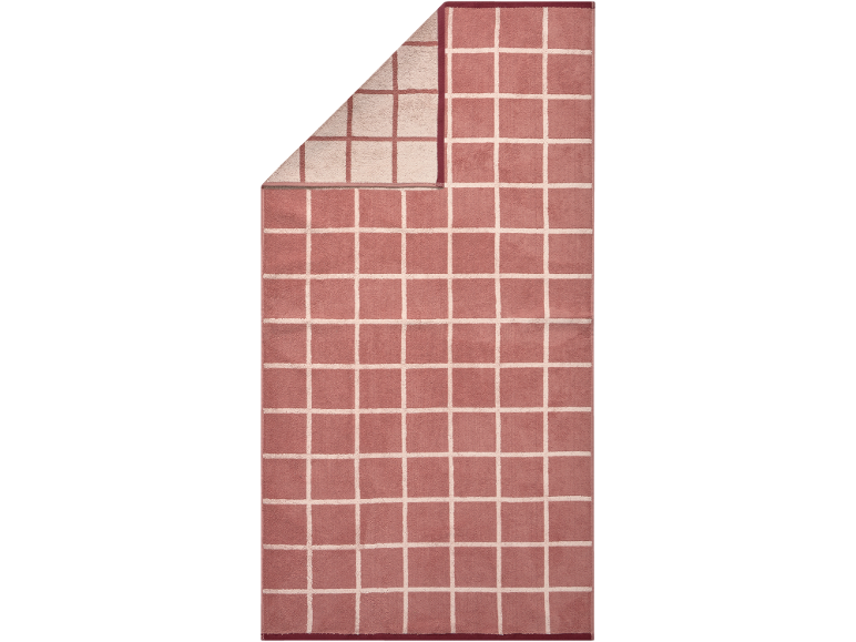 Tapis de bain rose à motif quadrillé blanc, partiellement plié pour montrer l'envers.