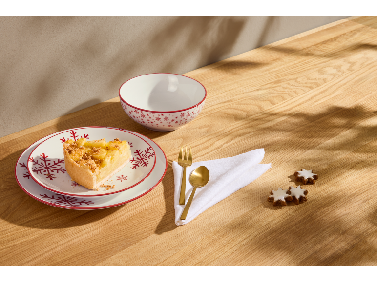 Assiettes de Noël avec une part de tarte, un bol et des biscuits sur une table en bois.