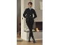 Femme en cardigan noir, col roulé et leggings, posant dans une pièce confortable.