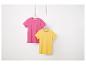 Deux t-shirts unis, rose et jaune, suspendus à des cintres.