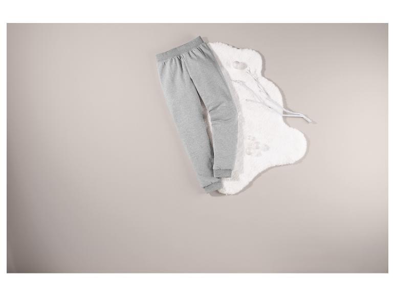 Pantalon de survêtement gris sur un fond blanc duveteux.