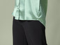 Une chemise en satin vert clair avec un pantalon noir.
