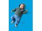 Bébé en gilet vert à capuche et pantalon bleu, avec un hochet bleu.