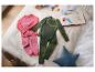 Deux ensembles de sous-vêtements thermiques pour enfants, un rose et un vert, sur une couverture avec des jouets.