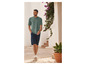 Homme en t-shirt vert et short bleu, marchant dehors.