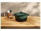 Cocotte en fonte verte sur un comptoir en bois.