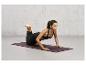 Une femme fait des pompes sur un tapis de yoga violet.