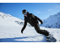 Snowboarder en veste et pantalon de ski noirs avec casque et lunettes sur montagne enneigée