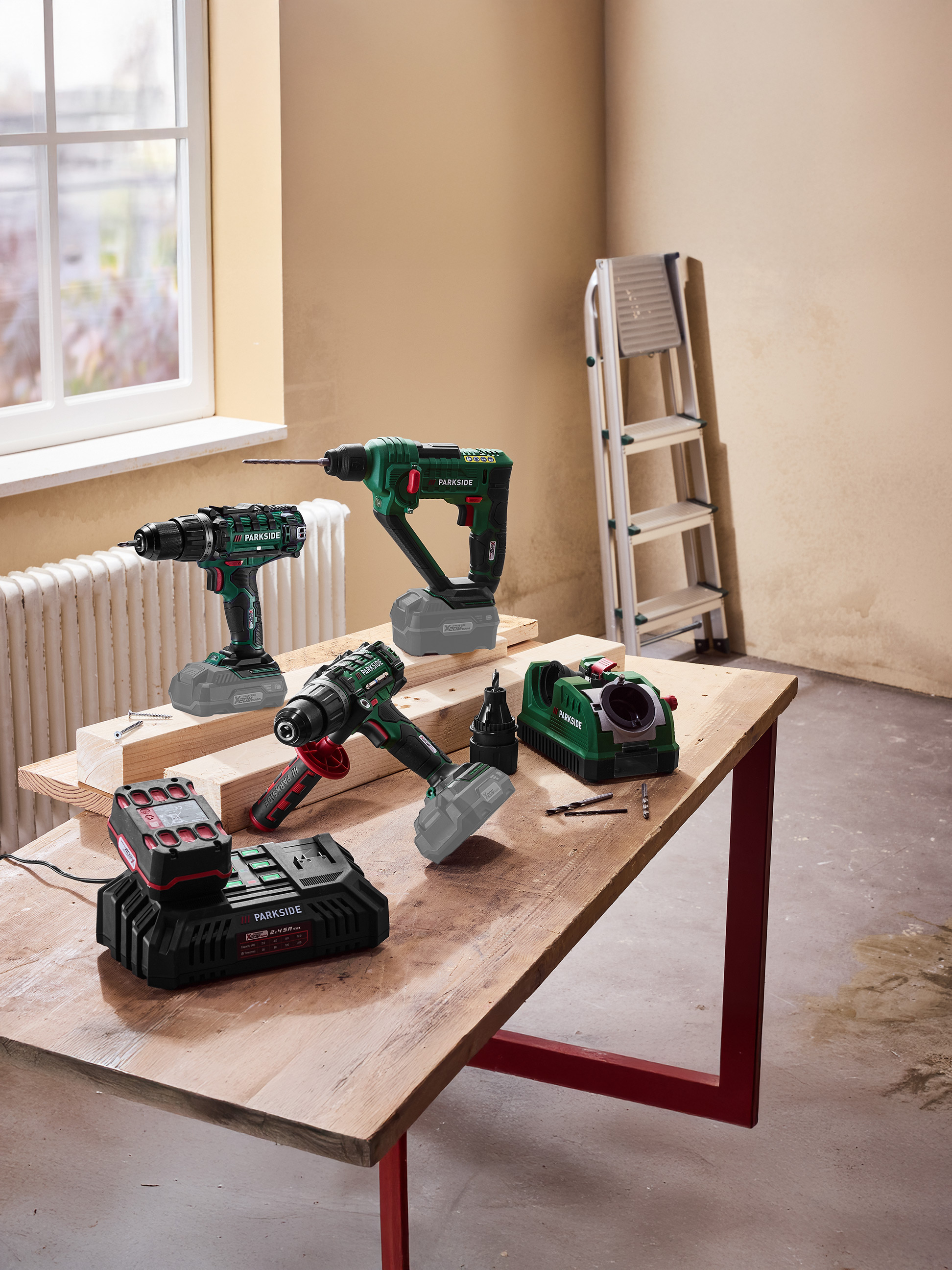 Outils électriques, y compris perceuses et chargeur de batterie, sur une table en bois.