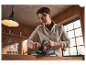 Une femme utilise une raboteuse Parkside pour travailler le bois dans son atelier.