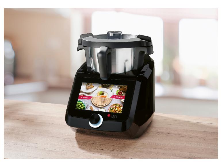 Robot de cuisine noir avec écran tactile affichant modes et recettes, sur un plan de travail en bois.