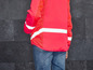 Une veste rouge avec des bandes réfléchissantes et un panneau en mesh.