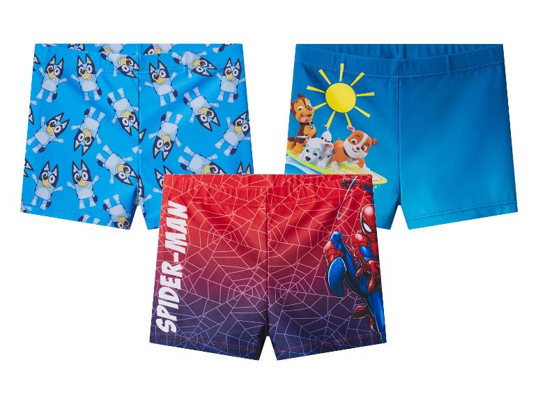 Trois maillots de bain pour enfants : bleu avec des chiens, bleu avec des chiots et rouge-bleu avec Spider-Man.