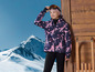 Une fille porte une veste de ski et un bonnet avec des lunettes de ski.