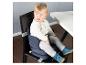 Bébé dans un rehausseur portable sur une chaise de salle à manger à côté d'une table blanche.