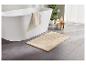 Tapis de bain beige moelleux près d'une baignoire.