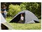 Homme avec sac de camping et femme dans une tente sur un camping herbeux.