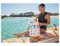 Femme en gilet de sauvetage ouvrant un sac à dos floral sur une planche de paddle.